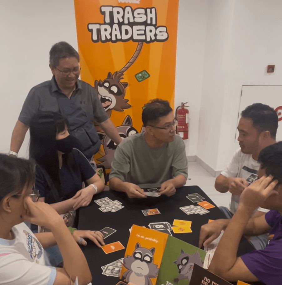 Friends playing Trash Traders at an event table